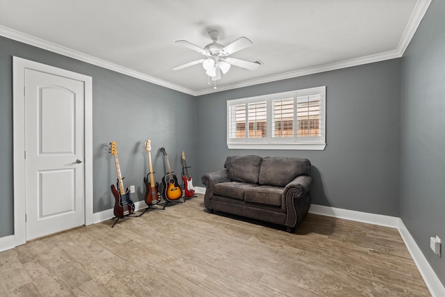 living area with light wood-style floors, crown molding, baseboards, and a ceiling fan