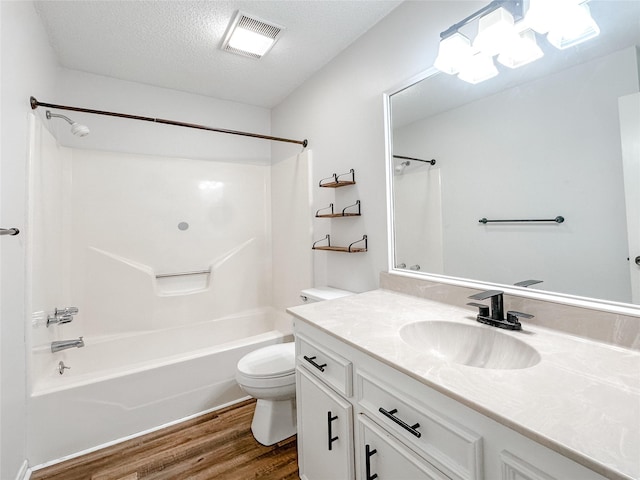 full bathroom with visible vents, toilet, wood finished floors, a textured ceiling, and washtub / shower combination