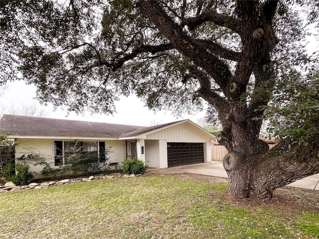 single story home with driveway, brick siding, an attached garage, and a front yard