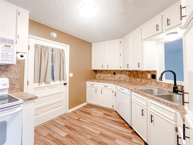 kitchen featuring white appliances, white cabinetry, light countertops, and a sink