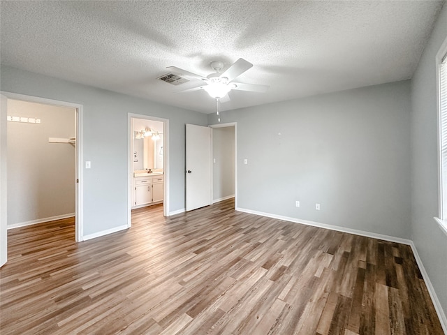 unfurnished bedroom with a spacious closet, a closet, light wood-type flooring, and baseboards