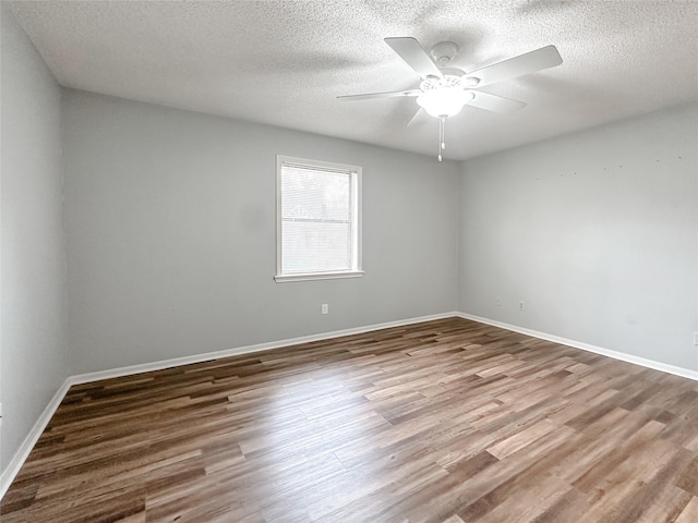 spare room with ceiling fan, a textured ceiling, baseboards, and wood finished floors