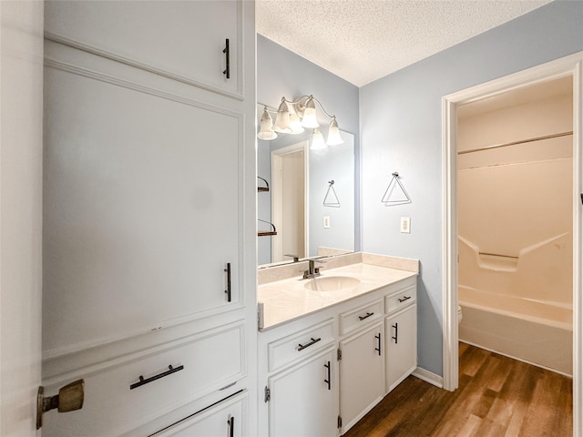 full bath featuring a textured ceiling, toilet, wood finished floors, and vanity