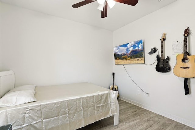 bedroom with a ceiling fan, baseboards, and wood finished floors