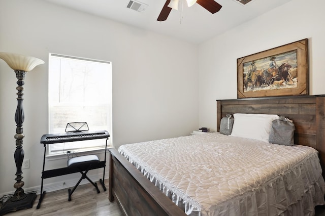 bedroom featuring a ceiling fan, baseboards, visible vents, and wood finished floors