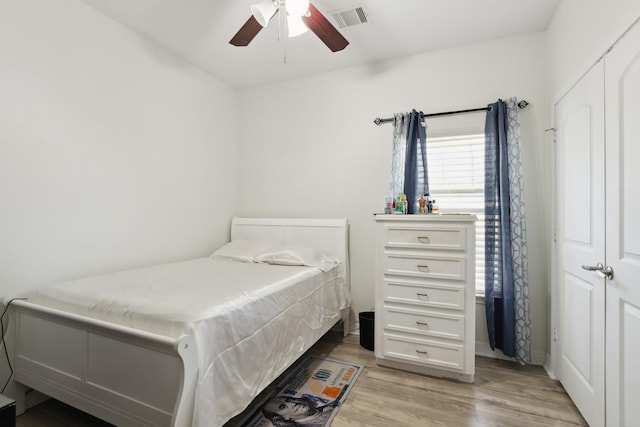 bedroom featuring light wood-style floors, visible vents, and a ceiling fan