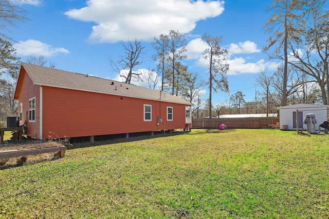 view of yard with an outdoor structure, central AC unit, a storage shed, and fence