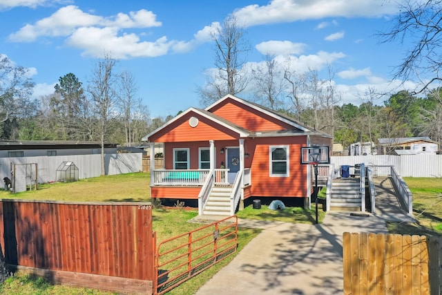 view of front facade with a porch, a fenced front yard, driveway, a gate, and a front yard