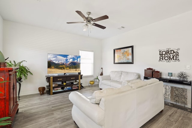 living room with ceiling fan, visible vents, baseboards, and wood finished floors