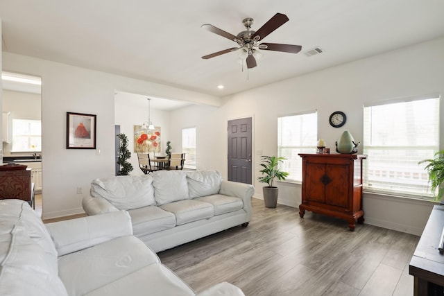 living room featuring ceiling fan, recessed lighting, visible vents, baseboards, and light wood-style floors