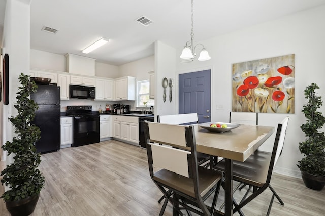 kitchen featuring white cabinetry, hanging light fixtures, visible vents, and black appliances