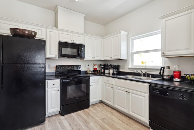 kitchen featuring dark countertops, black appliances, white cabinetry, and a sink