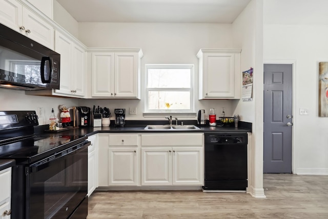 kitchen featuring dark countertops, light wood-style flooring, black appliances, white cabinetry, and a sink