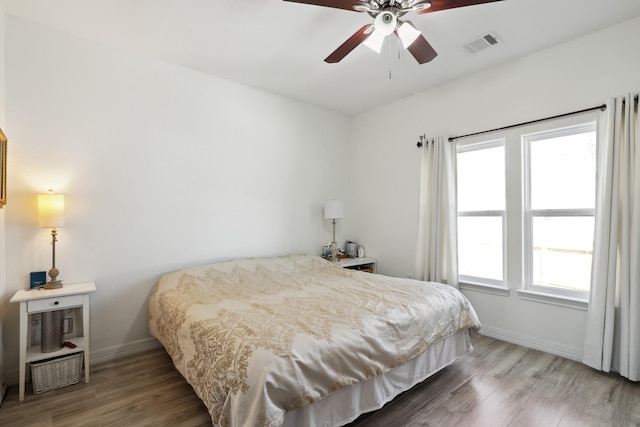 bedroom with visible vents, baseboards, and wood finished floors