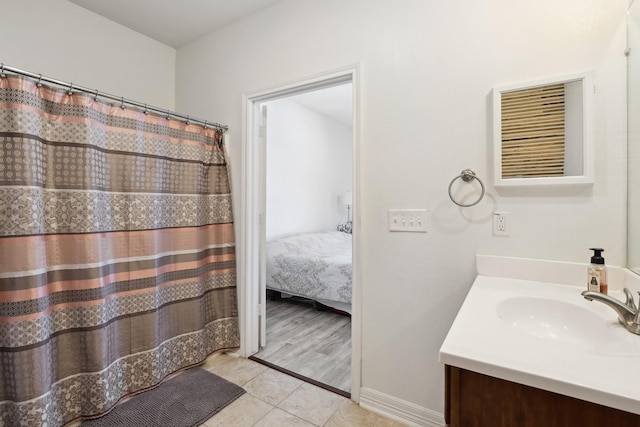 bathroom featuring tile patterned floors, vanity, baseboards, and ensuite bathroom