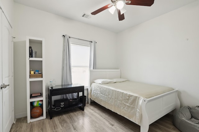 bedroom with a ceiling fan, visible vents, and wood finished floors