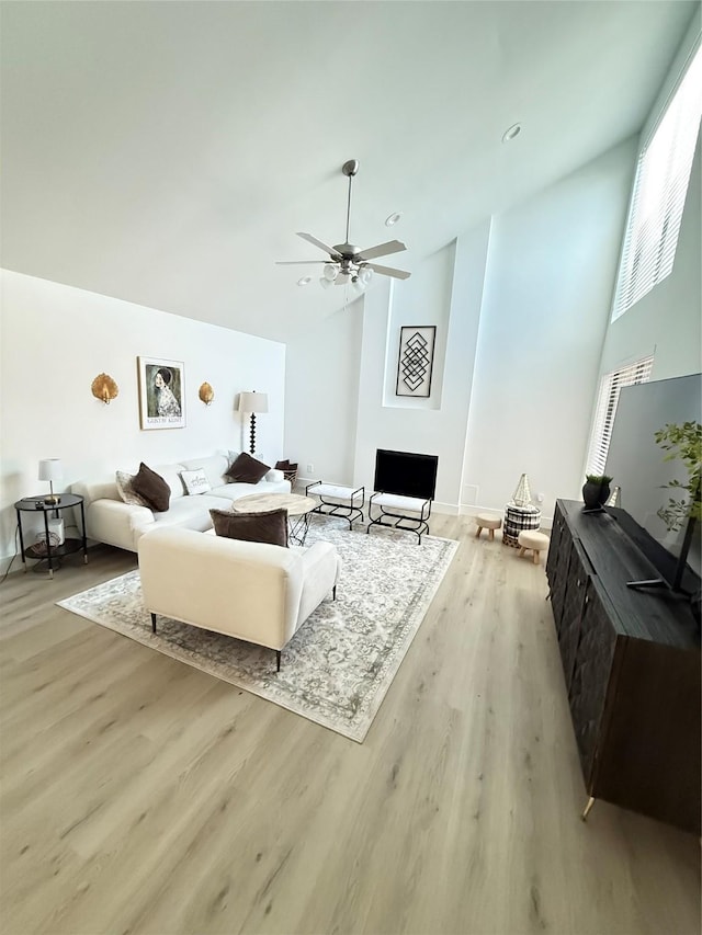 living area featuring light wood-style floors, high vaulted ceiling, and a ceiling fan