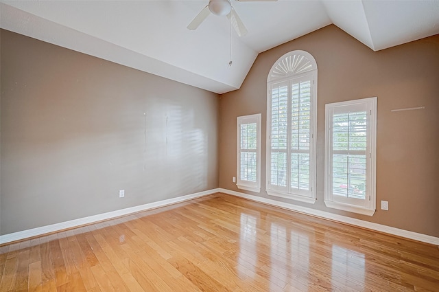 empty room featuring a ceiling fan, light wood-type flooring, vaulted ceiling, and baseboards