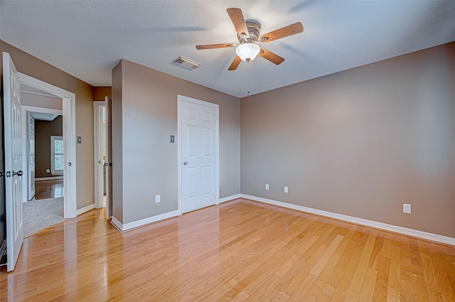 unfurnished bedroom with light wood finished floors, a ceiling fan, visible vents, and baseboards