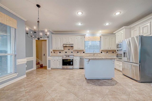 kitchen featuring appliances with stainless steel finishes, white cabinets, hanging light fixtures, and light stone counters