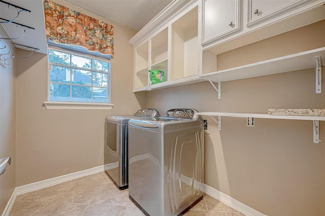 laundry area with washer and dryer, cabinet space, baseboards, and light tile patterned floors