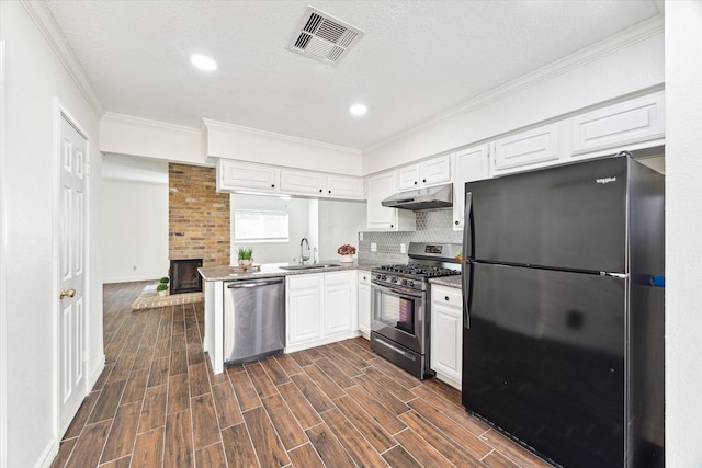 kitchen with under cabinet range hood, stainless steel appliances, a sink, visible vents, and wood tiled floor