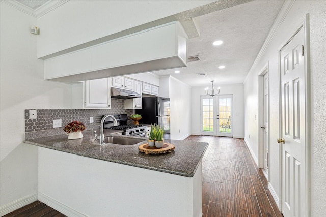 kitchen featuring dark wood-type flooring, visible vents, under cabinet range hood, and gas range