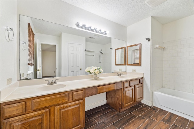 bathroom with a textured ceiling, double vanity, wood finish floors, and a sink