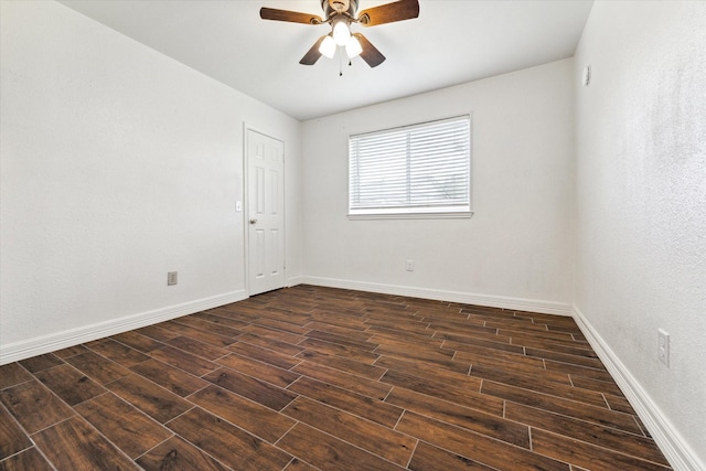 empty room featuring a ceiling fan, dark wood-style flooring, and baseboards