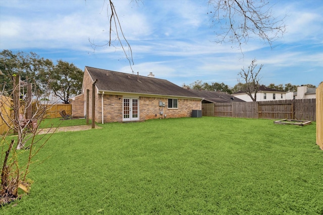 rear view of property with brick siding, a yard, and french doors