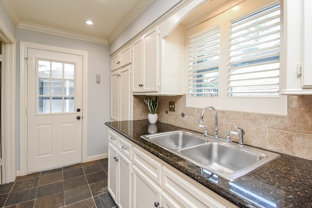 kitchen featuring a sink, white cabinetry, a healthy amount of sunlight, ornamental molding, and backsplash