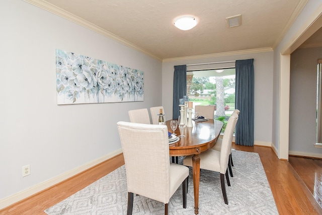 dining room featuring ornamental molding, visible vents, baseboards, and wood finished floors