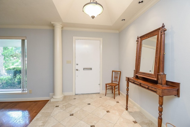 entryway with decorative columns, baseboards, and crown molding