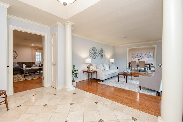 tiled living room with crown molding, decorative columns, and baseboards