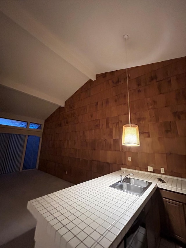 kitchen featuring vaulted ceiling with beams, a peninsula, tile counters, and a sink