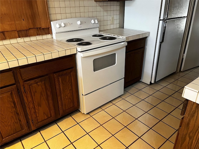 kitchen featuring white appliances, tasteful backsplash, tile counters, and light tile patterned flooring