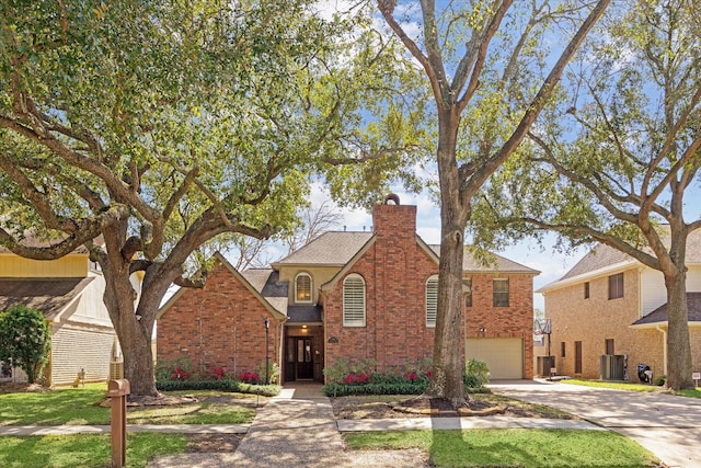 traditional-style home featuring brick siding, a chimney, an attached garage, central AC, and driveway