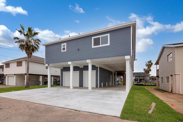 coastal home featuring a carport, a front lawn, an attached garage, and driveway