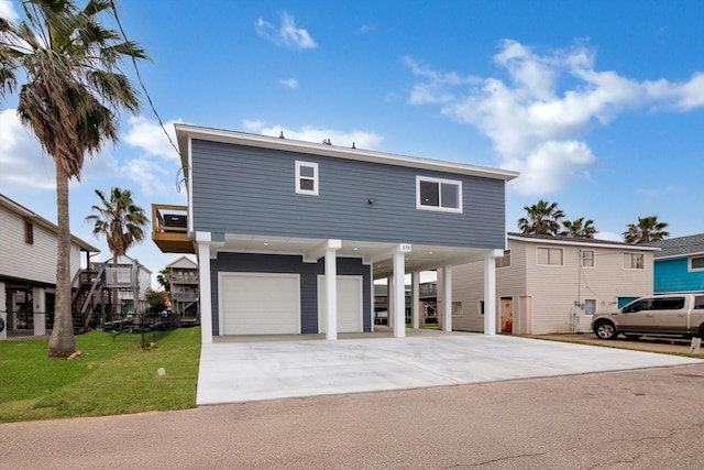 view of front facade with an attached garage, a front lawn, a carport, and concrete driveway