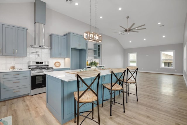 kitchen with a breakfast bar, light countertops, a center island, stainless steel gas stove, and decorative light fixtures