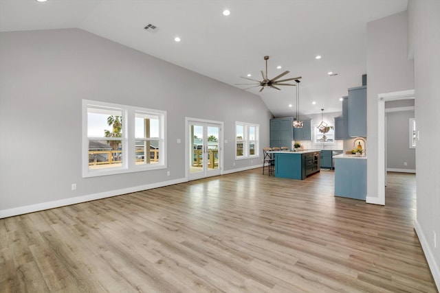 kitchen featuring decorative light fixtures, light countertops, open floor plan, blue cabinets, and a kitchen breakfast bar