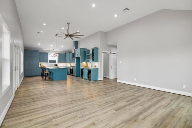 kitchen with a center island, blue cabinetry, light countertops, a barn door, and a kitchen breakfast bar