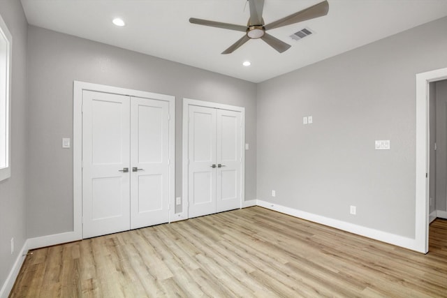 unfurnished bedroom with two closets, recessed lighting, visible vents, light wood-style floors, and baseboards