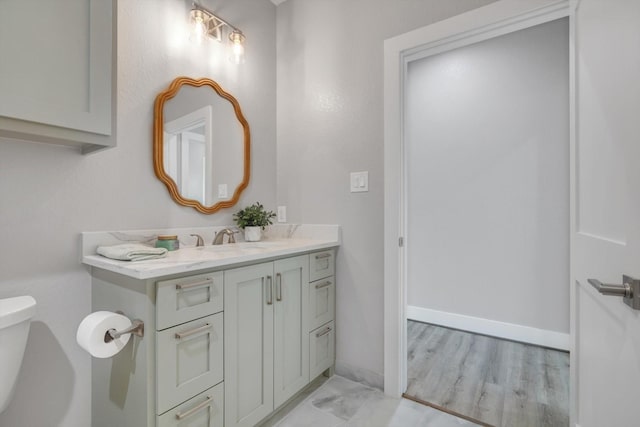bathroom featuring toilet, vanity, and baseboards