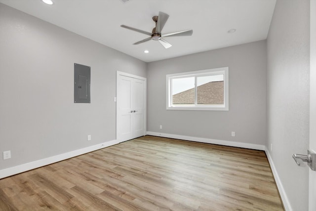 empty room with electric panel, baseboards, a ceiling fan, light wood-style floors, and recessed lighting