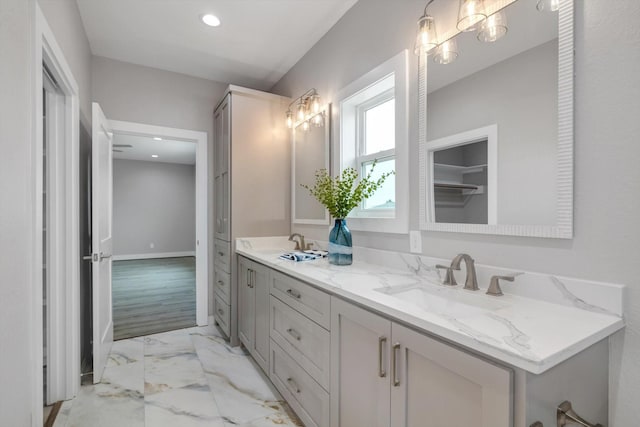 bathroom with marble finish floor, double vanity, recessed lighting, a closet, and a sink