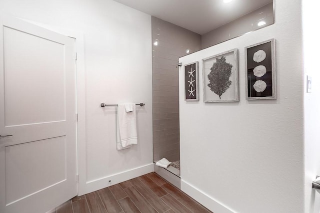 full bath with baseboards, a tile shower, and wood tiled floor