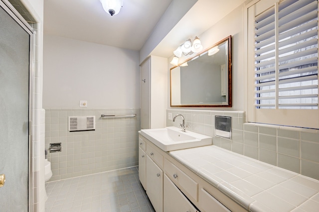 bathroom with toilet, a wainscoted wall, tile patterned flooring, vanity, and tile walls