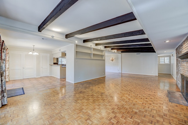 unfurnished living room featuring a chandelier, beamed ceiling, a fireplace, and baseboards