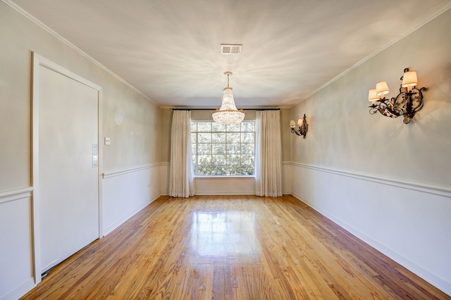 unfurnished dining area featuring light wood-style floors, visible vents, crown molding, and an inviting chandelier